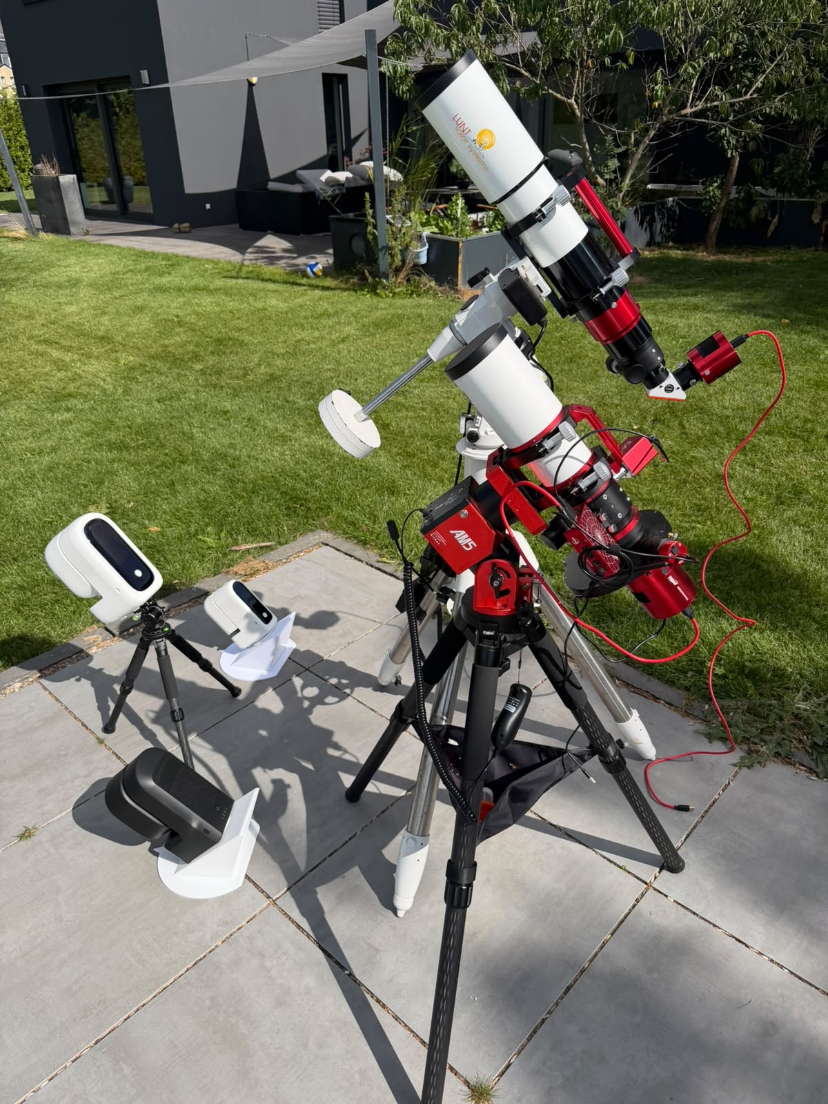 Two Seestar smart telescopes next to a refractor on an equatorial mount