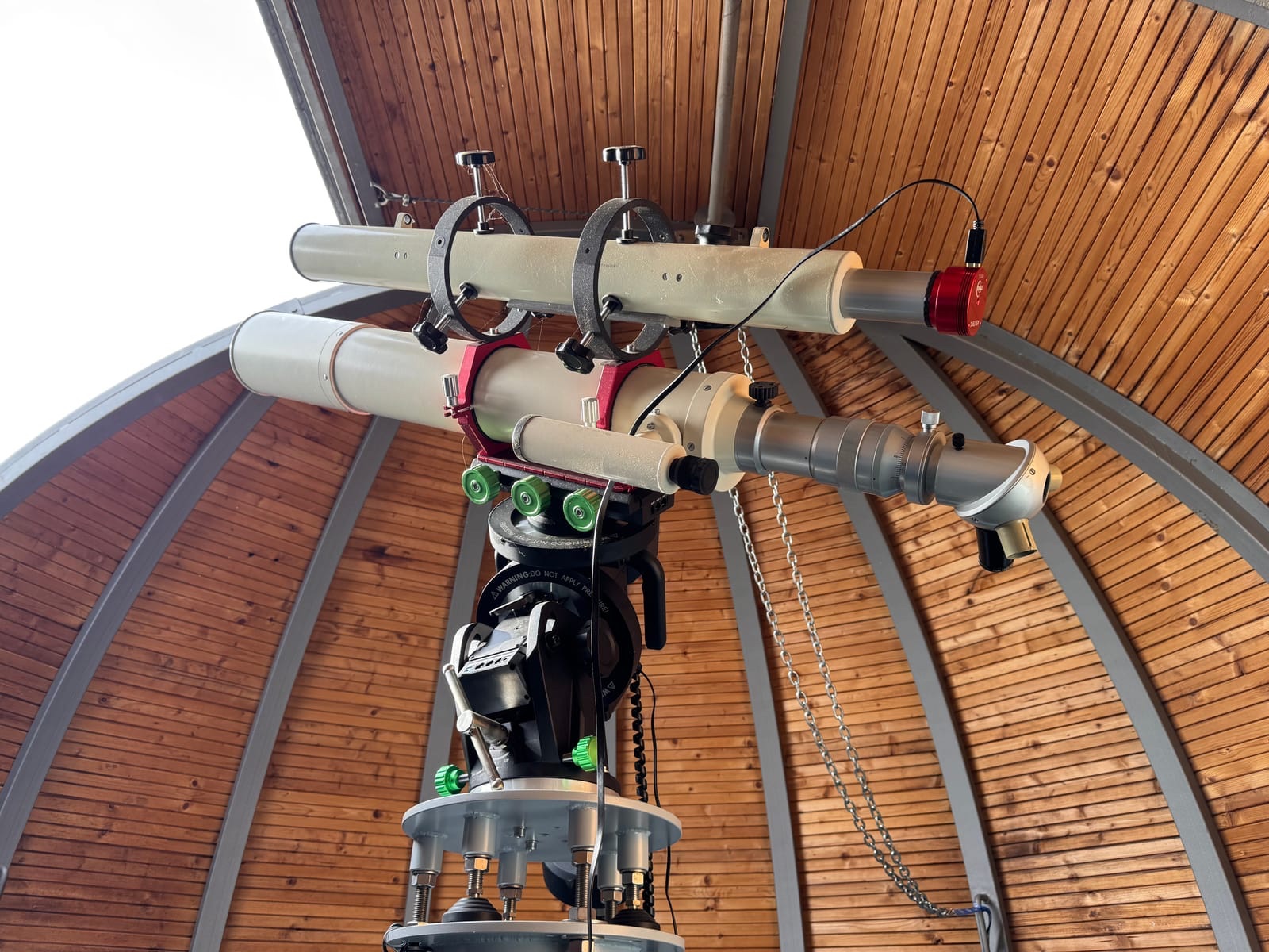 Refractor telescopes on a mount under the wooden dome of the Planetarium Chemnitz observatory